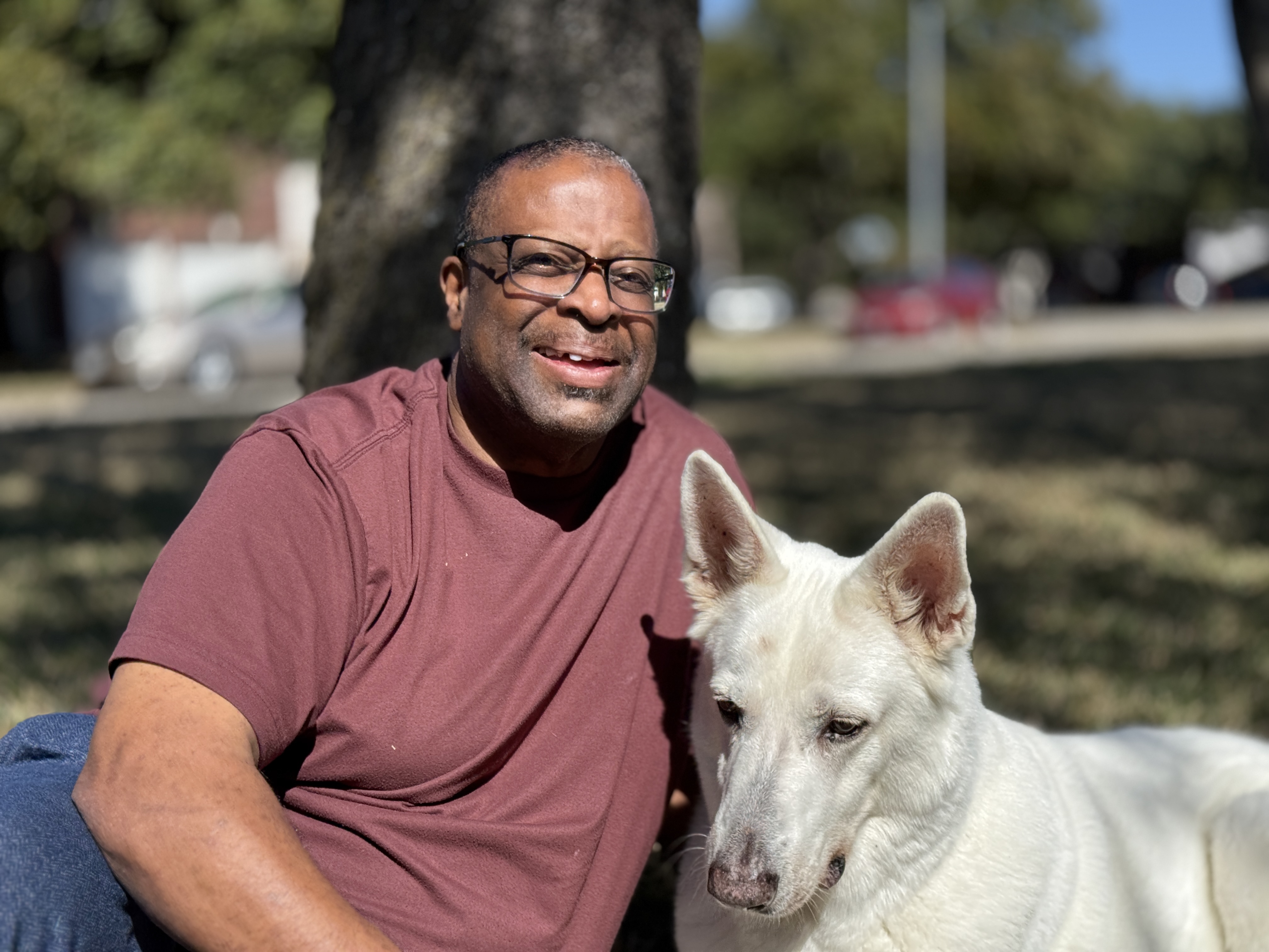 Samuel King sitting in a park with his white dog